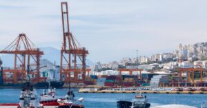 Cranes, stacked shipping containers and tugboats at the port of Piraeus.