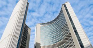 Toronto City Hall towers rising against a blue sky.
