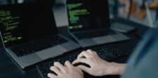 PHP Foundation says it has one full-time employee as security demands grow A person types on a keyboard in front of two laptops displaying code.