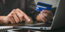 Compromised Shopify apps sent shoppers to fake checkout pages Person holding a blue credit card while typing on a laptop