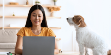 Small business finance management that keeps you cash-ready Small-business owner working on a laptop at home beside a dog, illustrating day-to-day financial management.