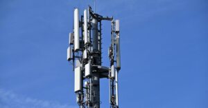 Cellular antennas and radio equipment mounted on a tower against a blue sky.