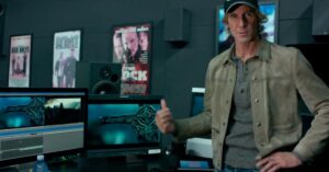 Michael Bay in an editing studio with Transformers footage visible on multiple monitors.