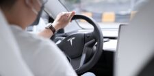 Tesla drops Full Self-Driving name in Europe after German pushback Driver holding the steering wheel inside a Tesla, illustrating the company’s shift from Full Self-Driving branding to Assisted Driving in Europe.