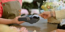 Customer tapping a card on a payment terminal held by a florist at a shop counter