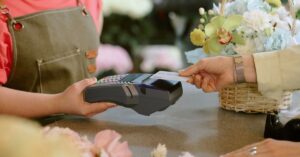 Customer tapping a card on a payment terminal held by a florist at a shop counter
