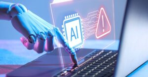 Robotic hand reaching toward a laptop keyboard beneath a holographic AI chip and warning sign