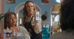 Hair stylist showing the Xero logo on a smartphone in an official Xero small-business accounting video.
